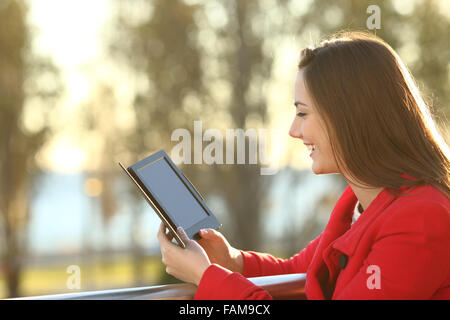 Donna di lettura di un ebook in un balcone al tramonto in inverno Foto Stock