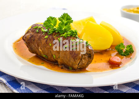 Gustosi involtini di carne di manzo sulla piastra con patate, salsa, close up Foto Stock