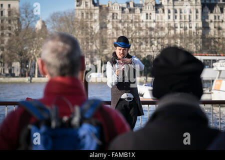 Sulla South Bank di Londra un busker intrattiene il pubblico con un trucco di magia. Foto Stock