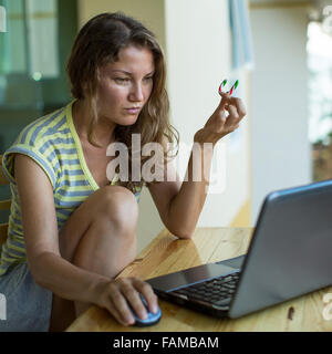 Giovane donna che lavorano su computer portatile sulla veranda. Foto Stock