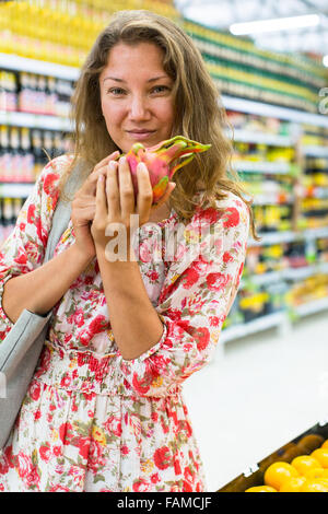 Giovane donna si erge in un supermercato con Pitaya (dragon frutta) nelle sue mani. Foto Stock