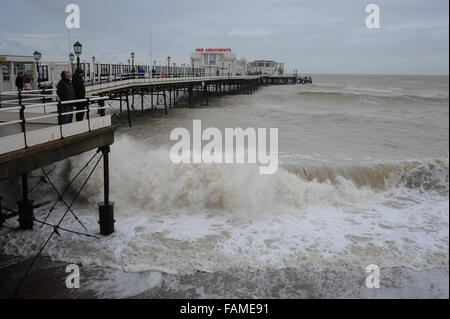 Persone stand su Worthing Pier e guardare le grandi onde che si infrangono sulla spiaggia il giorno di nuovi anni in Worthing West Sussex, in Inghilterra. Foto Stock