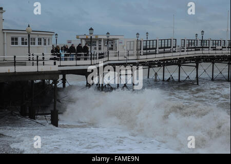 Persone stand su Worthing Pier e guardare le grandi onde infrangersi sulla spiaggia il giorno di nuovi anni in Worthing West Sussex, in Inghilterra. Foto Stock
