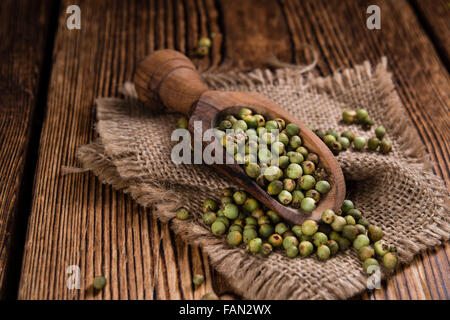 Porzione di grani di pepe verde (close-up shot) su sfondo di legno Foto Stock