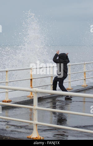 Aberystwyth, Wales, Regno Unito. Il 2 gennaio, 2016. Regno Unito: Meteo nonostante una tregua nei recenti tempeste un notevole rigonfiamento genera drammatica onde si infrangono contro la promenade. Qui un giovane ragazzo è visto schivare le onde. Credito: Alan Hale/Alamy Live News Foto Stock