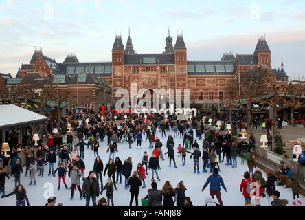 La folla di persone pattinaggio stagionale sul campo di pattinaggio a Museumplein (Museum Square), Amsterdam, Paesi Bassi. Rijksmuseum in retro Foto Stock