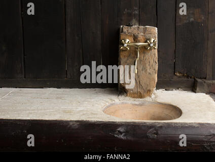 Rubinetto cromato e un lavandino in un ceppo di legno decord da una casa tradizionale Foto Stock