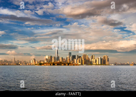 La parte inferiore di Manhattan il Quartiere Finanziario di grattacieli, One World Trade Center e Ellis Island nel tardo pomeriggio dal Porto di New York Foto Stock