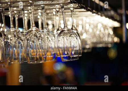 Svuotare bicchieri da vino appeso sulla barra rack con sfondo bokeh. ristorante moderno, utensili da cucina o una cena romantica nozione Foto Stock