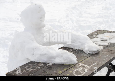 Lonely snow uomo seduto al tavolo da picnic in inverno Foto Stock