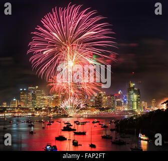 Nuovo anno fuochi d'artificio a Sydney da elevati lookout a Berrys bay oltre il porto di Sydney CBD con grattacieli sotto le sfere di flash Foto Stock