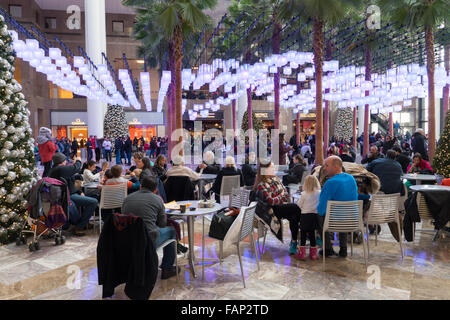 Ai visitatori e agli acquirenti di sedersi sotto lanterne pendenti nell'atrio di Brookfield luogo durante la stagione di vacanza a New York City. Foto Stock