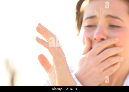 Donna che piange durante la visione di un anello di fidanzamento dopo la proposta in una giornata di sole Foto Stock