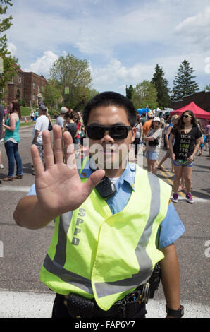 Giovani asiatici riserva americana poliziotto tenendo la mano fino a fermare il traffico. Grand Old giorno Street Fair. St Paul Minnesota MN USA Foto Stock
