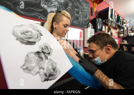 Aesch, Svizzera. 14 Ago, 2015. Dennis Weber (R), un uomo con nanismo, tatuaggi Ramona Hopfner in un tattoo studio in Aesch, Svizzera, 14 agosto 2015. Molte persone con nanismo affrontare problemi durante la ricerca di un lavoro. Foto: PATRICK SEEGER/dpa/Alamy Live News Foto Stock