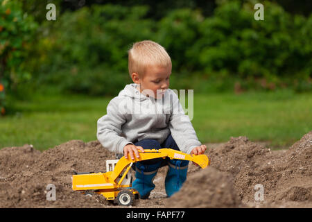 Little Boy a giocare con i bambini escavatore in sandbox. Foto Stock