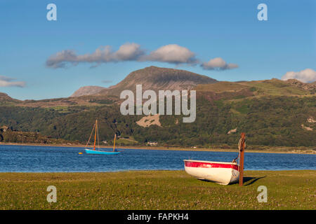 Un bando di gara è redatto sul lato del Mawddach estuary con una piccola barca a vela ormeggiata su l'acqua dominato da montagne. Foto Stock