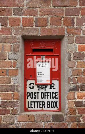 La scatola a muro di Ludlow. Un britannico tradizionale montato a parete red letterbox dal regno di George V. In Moreton village. Il Dorset, Inghilterra, Regno Unito. Foto Stock