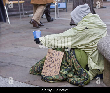 Uomo senza tetto con segno su una strada mendicando Foto Stock