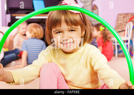 Sorridente bambina di sedersi con hoop sorriso e felice Foto Stock