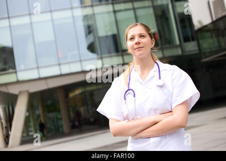 Giovane medico in piedi con le braccia incrociate Foto Stock