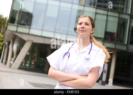 Giovane medico in piedi con le braccia incrociate Foto Stock