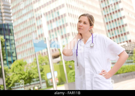 Giovane medico che soffrono di dolore al collo dopo una stressante giornata di lavoro Foto Stock