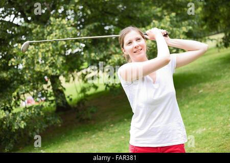 Giovane donna giocando a golf Foto Stock