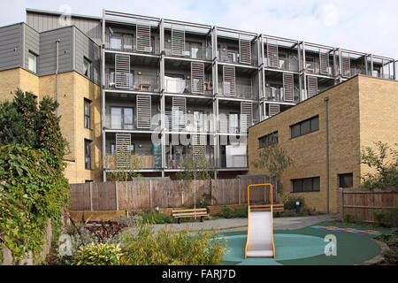 Un piccolo giardino e area gioco per bambini dietro un nuovo blocco di appartamenti a Hackney, a est di Londra Foto Stock