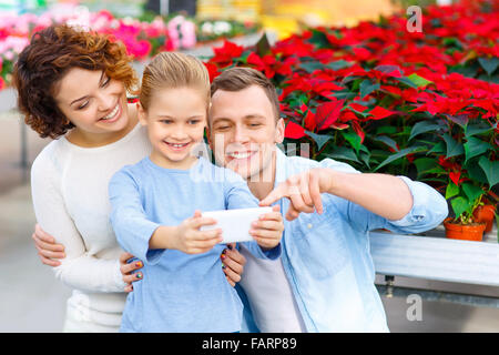 Famiglia giovane tenendo selfies in serra Foto Stock