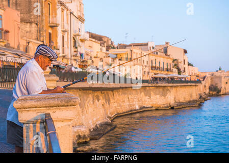 La pesca della Sicilia, la vista di un uomo anziano dalla pesca in alto mare la parete che si affaccia sul porto di Ortigia, Siracusa (Siracusa), Sicilia. Foto Stock