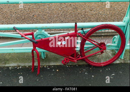 Resti di insolito rosso bicicletta incatenato al verde di ringhiere, Brighton, Regno Unito Foto Stock