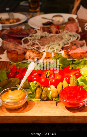Diversi tipi di carne e verdure e spezie su un tavolo in un ristorante esterno. Tempo soleggiato Foto Stock