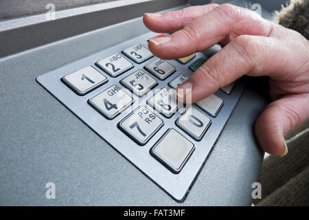 Il calettamento della donna nel suo PIN a un bancomat. Foto Stock