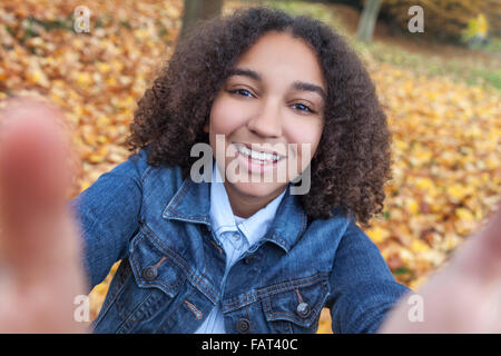 Bella felice razza mista americano africano ragazza adolescente bambino femmina sorridente con denti perfetti tenendo selfie fotografia Foto Stock