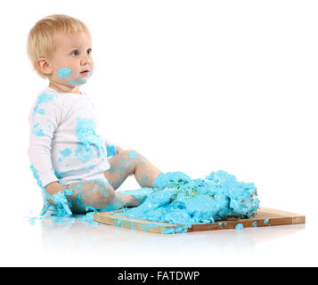 Da un anno un bimbo smashing un blu iced torta di compleanno su una tavola di legno. Immagine è isolato su uno sfondo bianco. Foto Stock