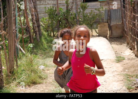 Due ragazze che corre lungo il percorso in un quartiere di luperon,Repubblica dominicana. Foto Stock