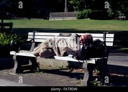 Senzatetto dormire su una panchina nel parco, del centro cittadino di Vancouver, BC, British Columbia, Canada Foto Stock