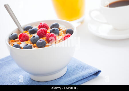 Una sana colazione con muesli, frutti di bosco freschi, succo d'arancia e una tazza di caffè. Profondità di campo, concentrarsi su bacche e m Foto Stock