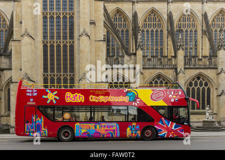 Open top sightseeing bus e Abbazia di Bath in background, Somerset, Regno Unito Foto Stock