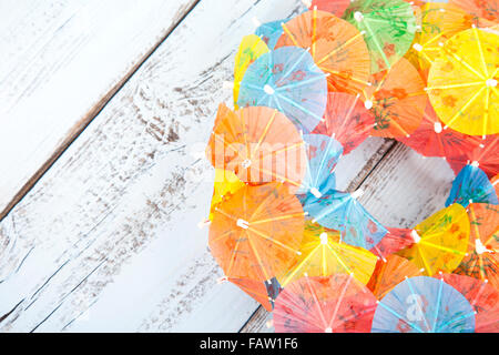 Piccola festa ombrelloni nel cerchio di luce blu sullo sfondo di legno Foto Stock