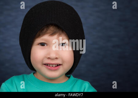 Un sorridente giovane ragazzo che indossa una maglia Cappello invernale. Foto Stock