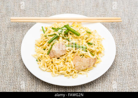 La carne di maiale Chow Mein con bacchette in piastra bianca. Foto Stock