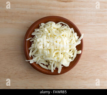 Vista dall'alto di una porzione di una scarsa umidità tutta la mozzarella di latte Formaggio per pizza in una piccola ciotola in cima a una tavola di legno Foto Stock