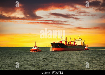 Rimorchiatori assistere nave da carico sul mare al mattino. Foto Stock