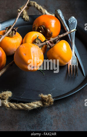 Persimmons maturi frutti su sfondo rustico Foto Stock