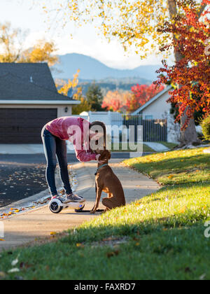 REDDING, CA, Stati Uniti d'America - 24 novembre 2015: ragazza adolescente passeggiate cane con auto-bilanciare due-scooter a ruote, chiamato anche un hoverboard. Foto Stock