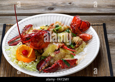 Vicino la vista frontale di un appena cotti interi Maine lobster coperto con erbe, cipolle e salsa su piastra bianca. Foto Stock