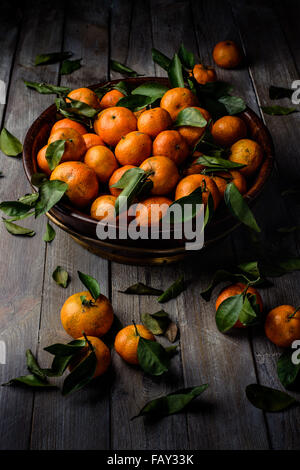Moody basso-chiave studio shot di mandarini in una ciotola di legno Foto Stock