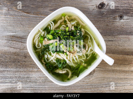 Alta Vista angolato di noodle e zuppa di verdure con il cucchiaio nella ciotola di legno rustico. Foto Stock